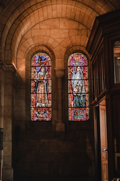 Volunteers cleaning stained glass windows inside a church.