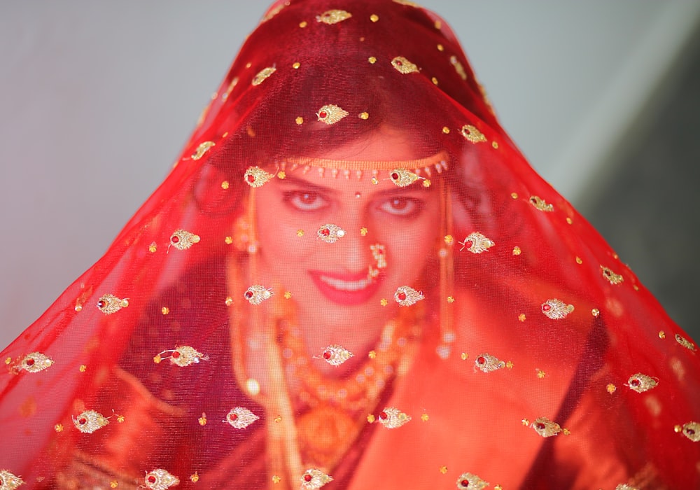 a woman wearing a red veil and gold jewelry