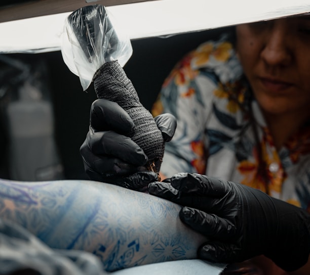 a woman getting her tattoo done by a tattoo artist