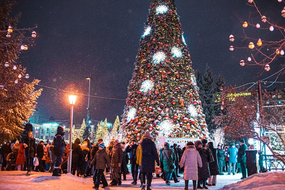 a crowd of people standing around a christmas tree