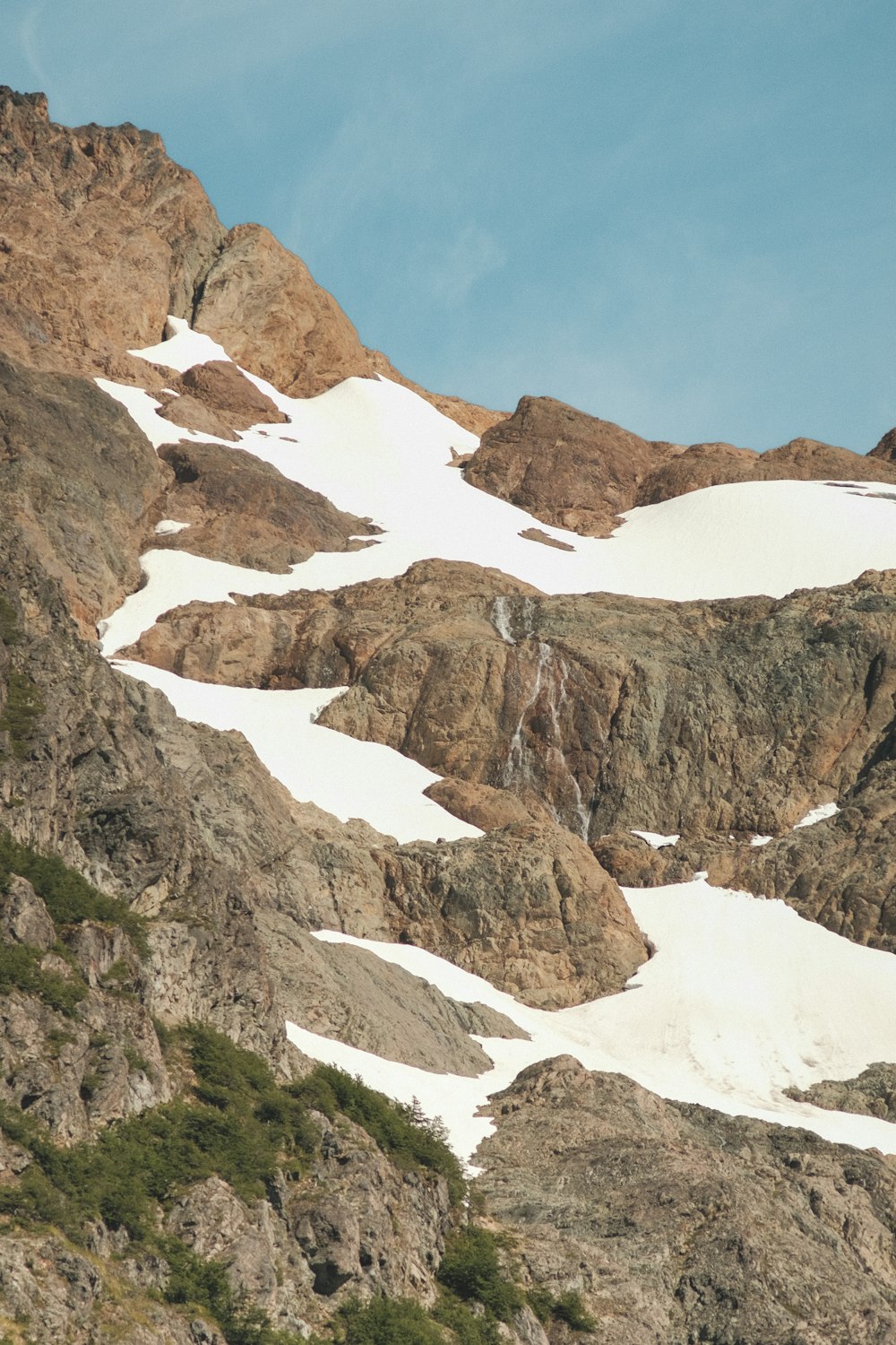 a mountain covered in snow and rocks under a blue sky