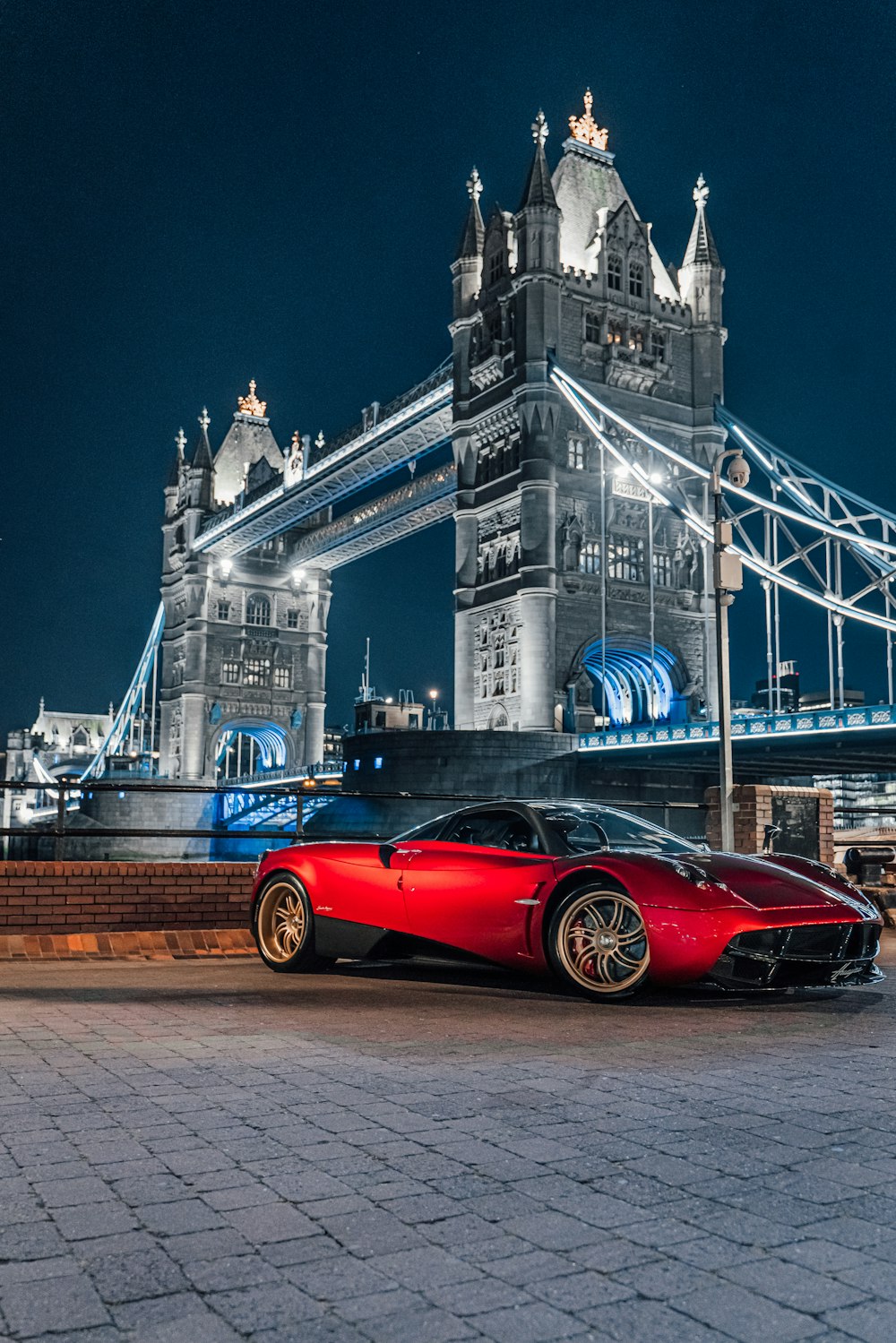a red sports car parked in front of a bridge