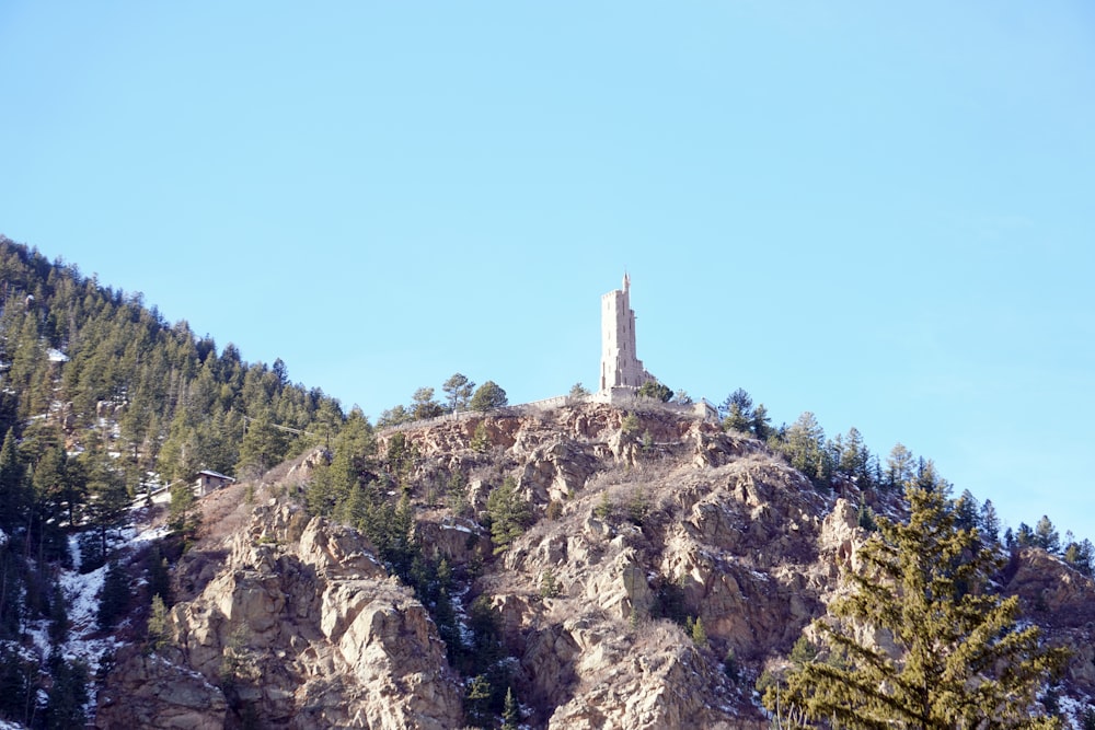 a tall tower on top of a mountain surrounded by trees