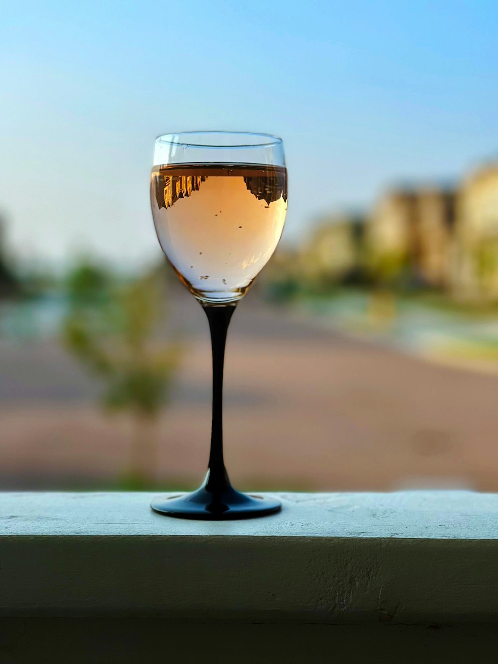 a glass of wine sitting on top of a window sill