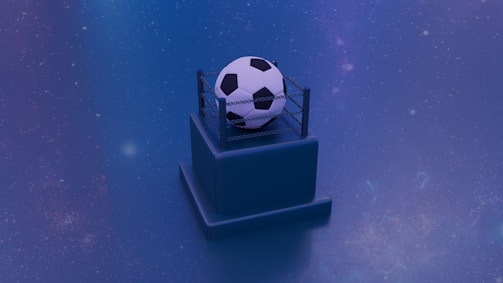 A soccer ball is placed atop a small pedestal encircled by a miniature wrestling ring. The background is a starry blue gradient, giving the scene an otherworldly appearance with a touch of mystery.