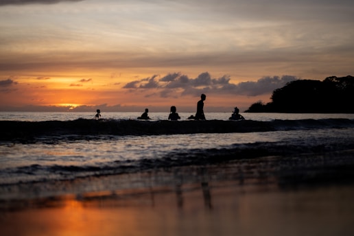a group of people sitting on top of a beach next to the ocean