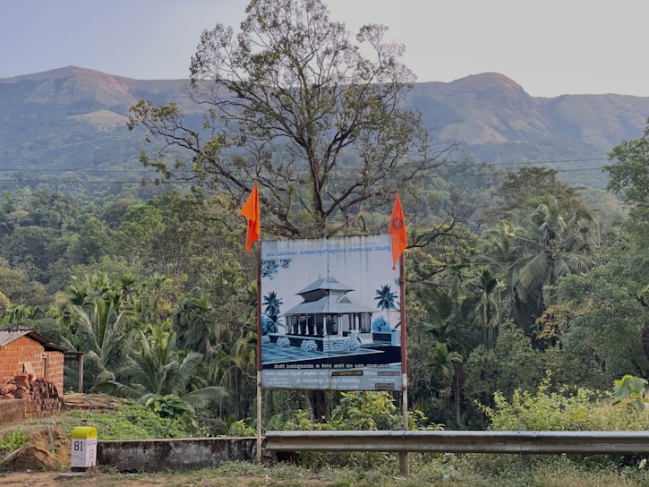 A vibrant land promoting project signboard displayed on a cleared plot of land with cityscape in the background.