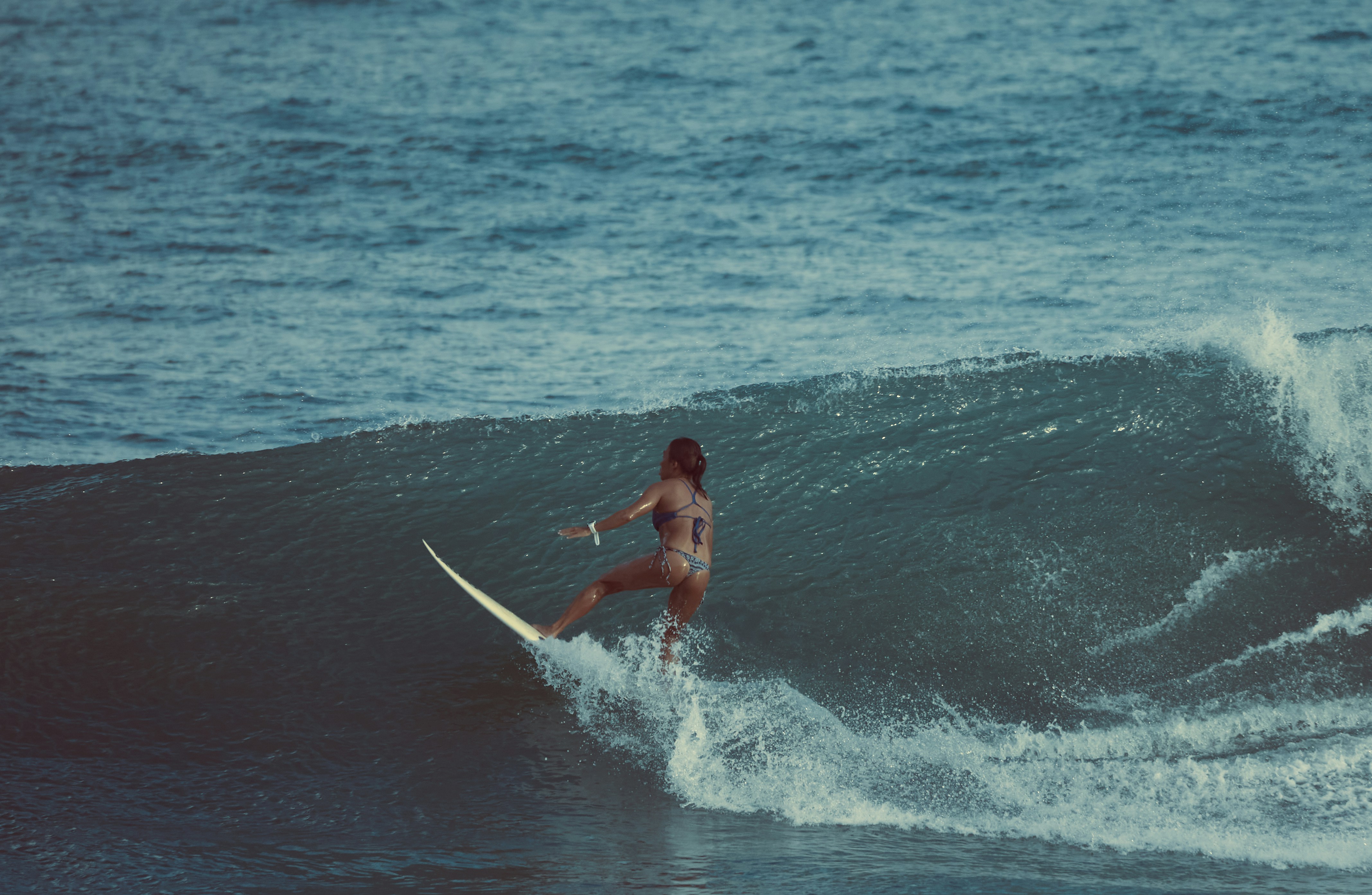 a woman riding a wave on top of a surfboard