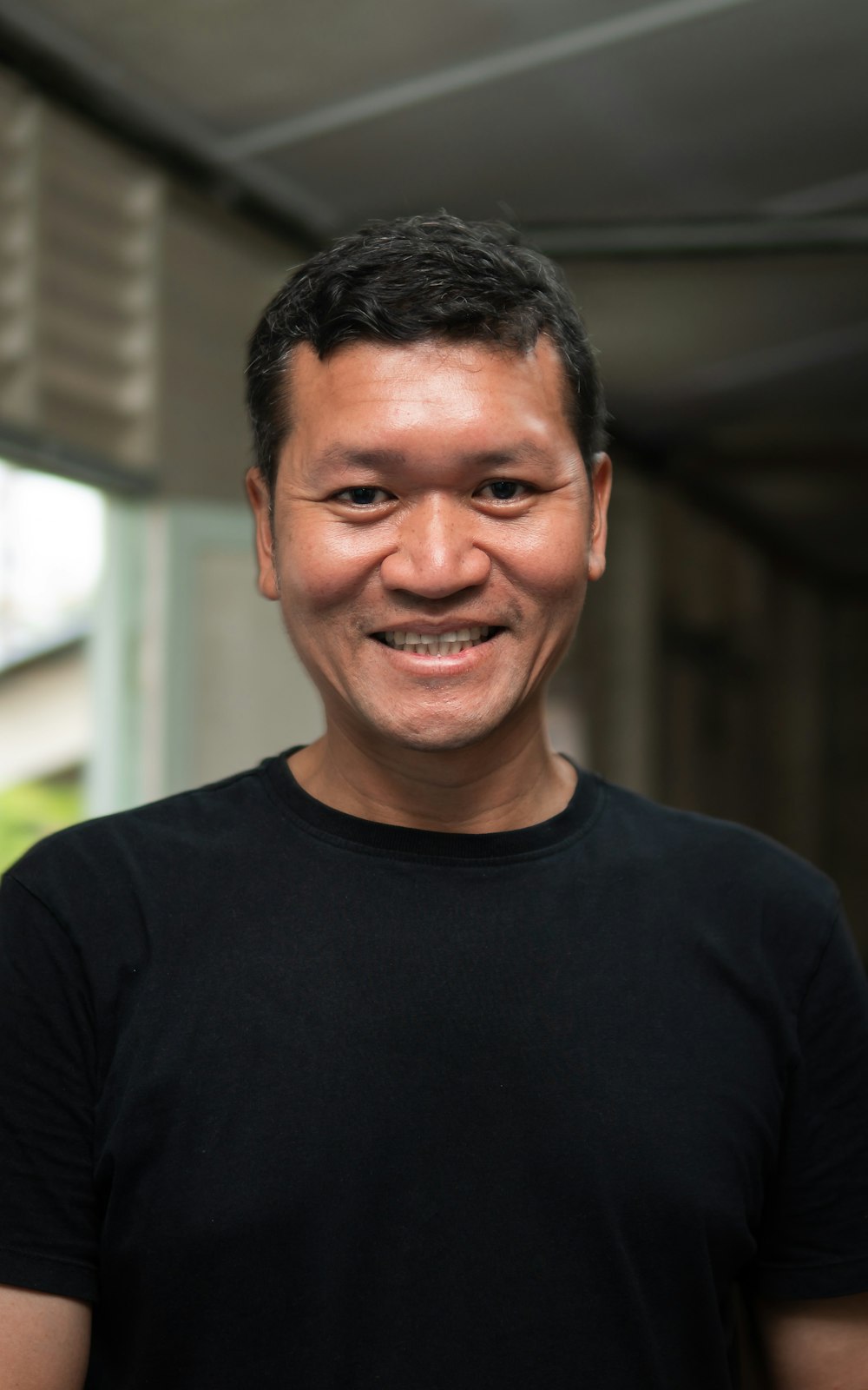 a man in a black shirt smiling at the camera