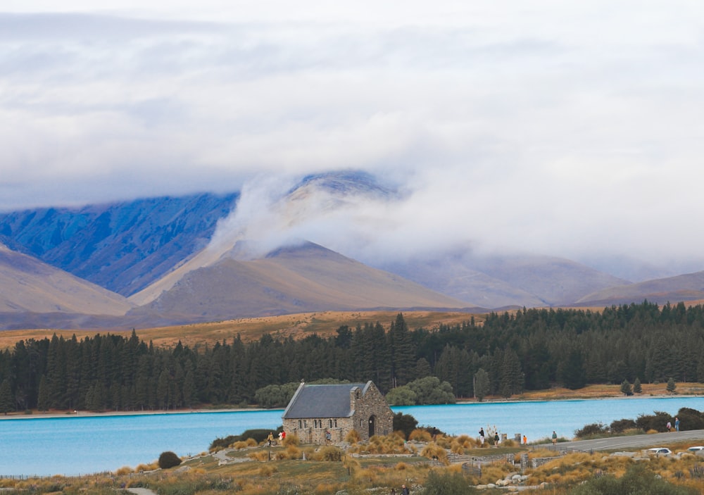 a house on the side of a lake with mountains in the background