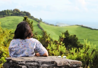 a woman sitting on top of a stone wall