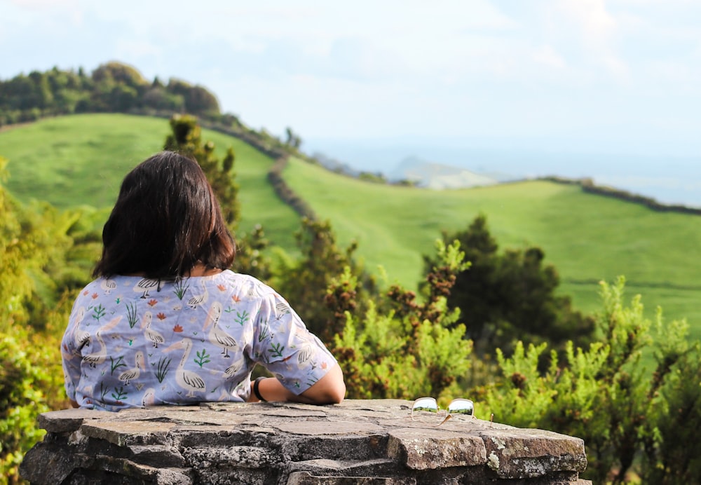 a woman sitting on top of a stone wall