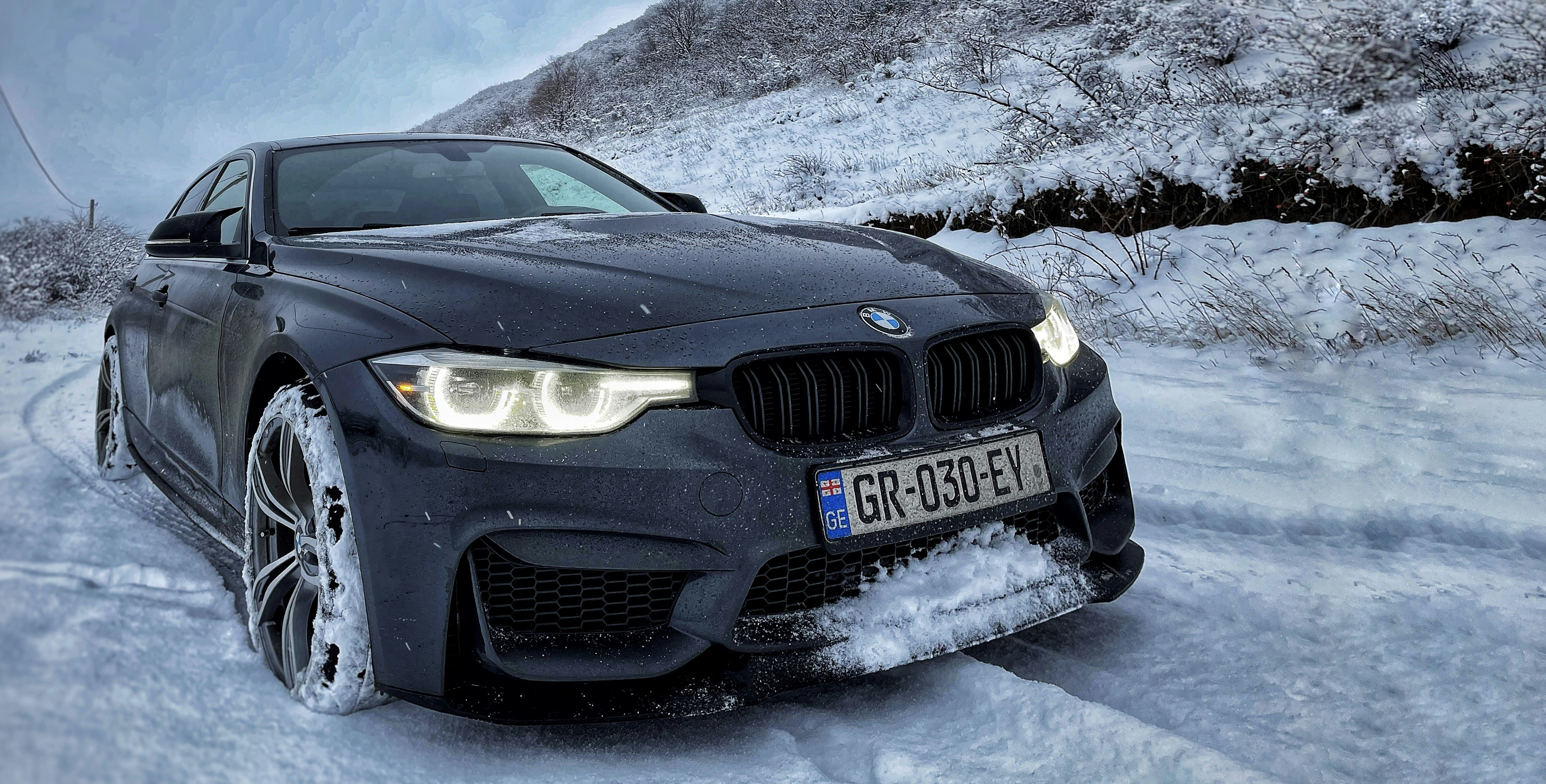 A black car driving down a snow covered road photo – Free Bumper Image ...