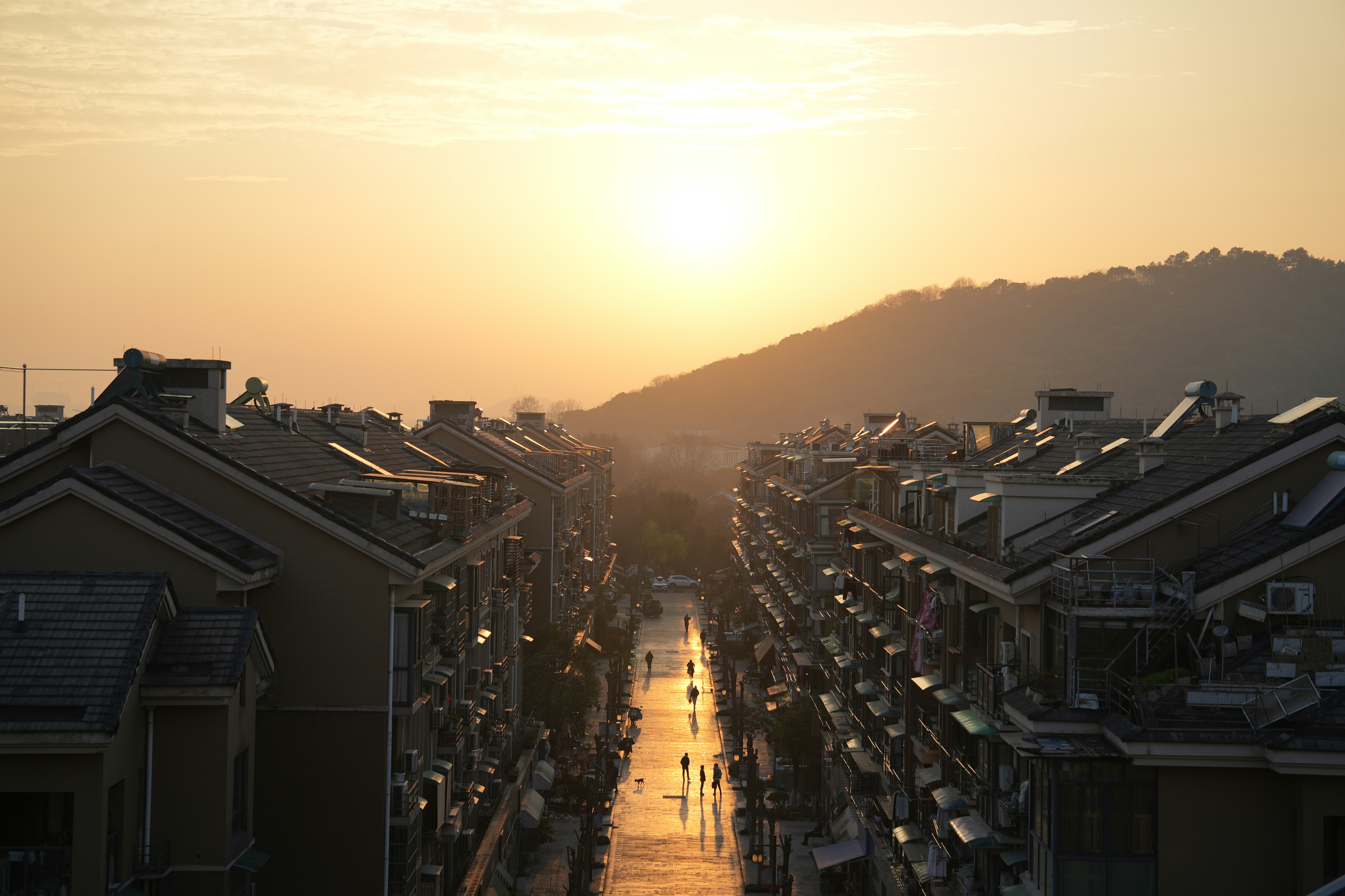 the sun is setting over a row of houses