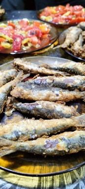 A colorful plate of freshly fried fish served with lemon wedges and a side salad.