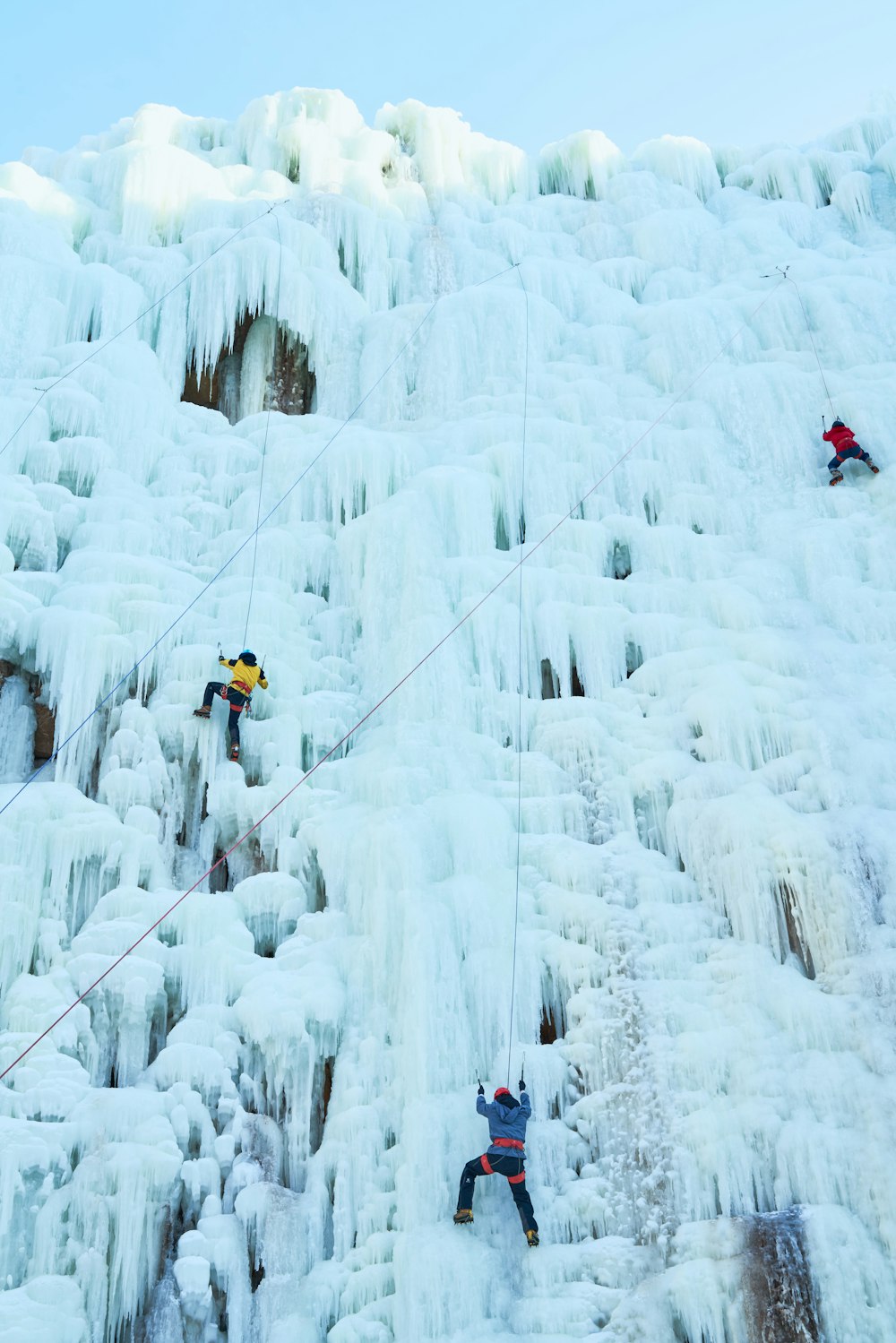 a group of people climbing up the side of a snow covered mountain