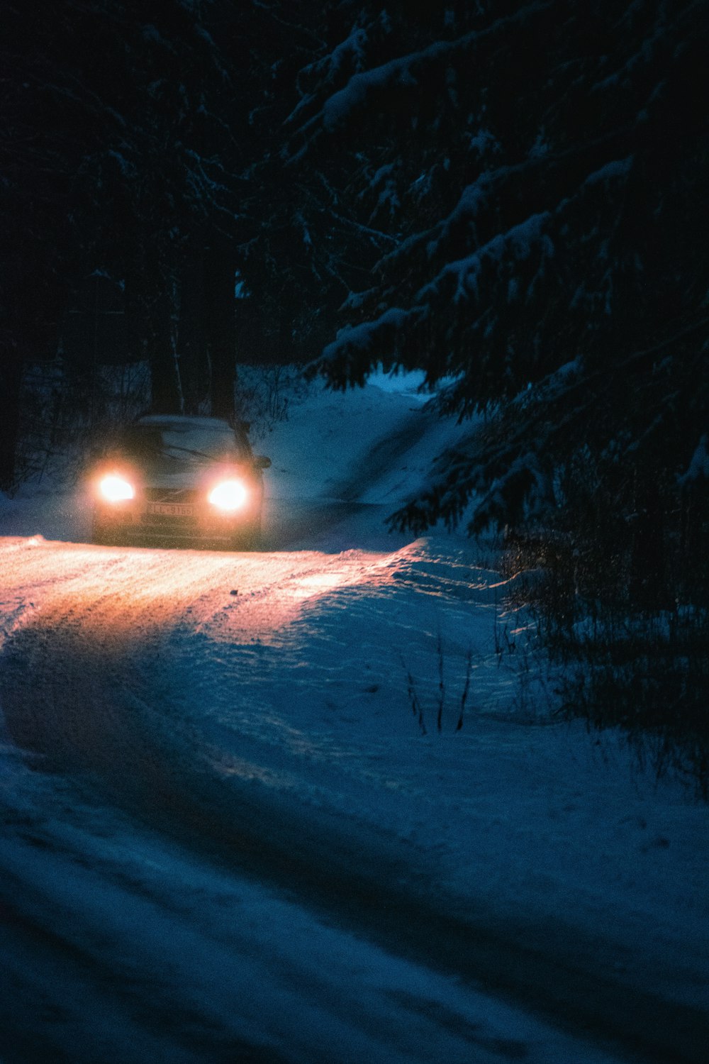 a car driving down a snowy road at night