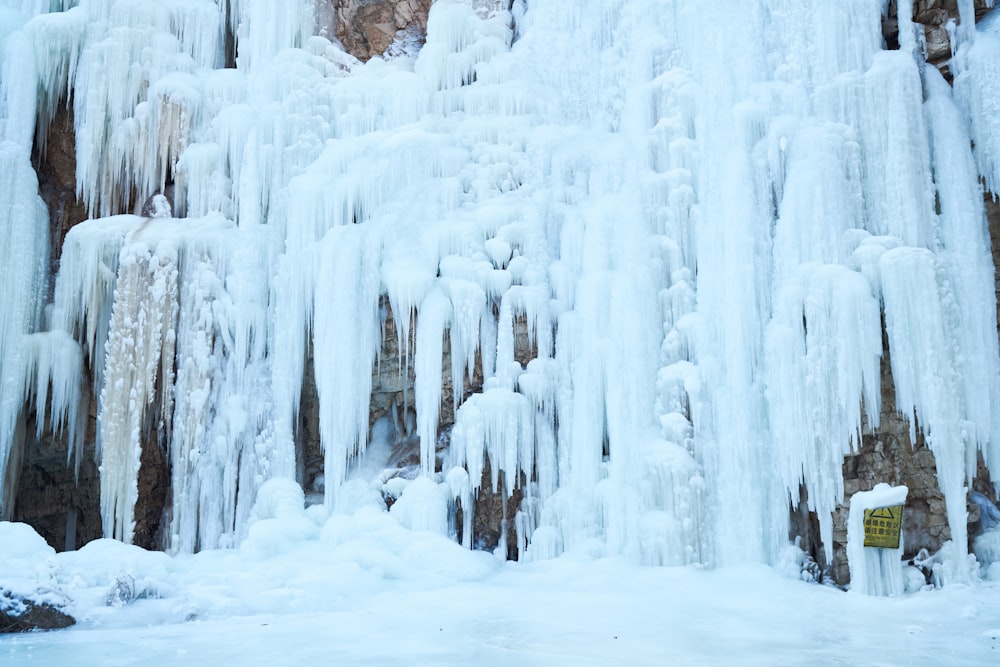 a man standing in front of a waterfall covered in ice