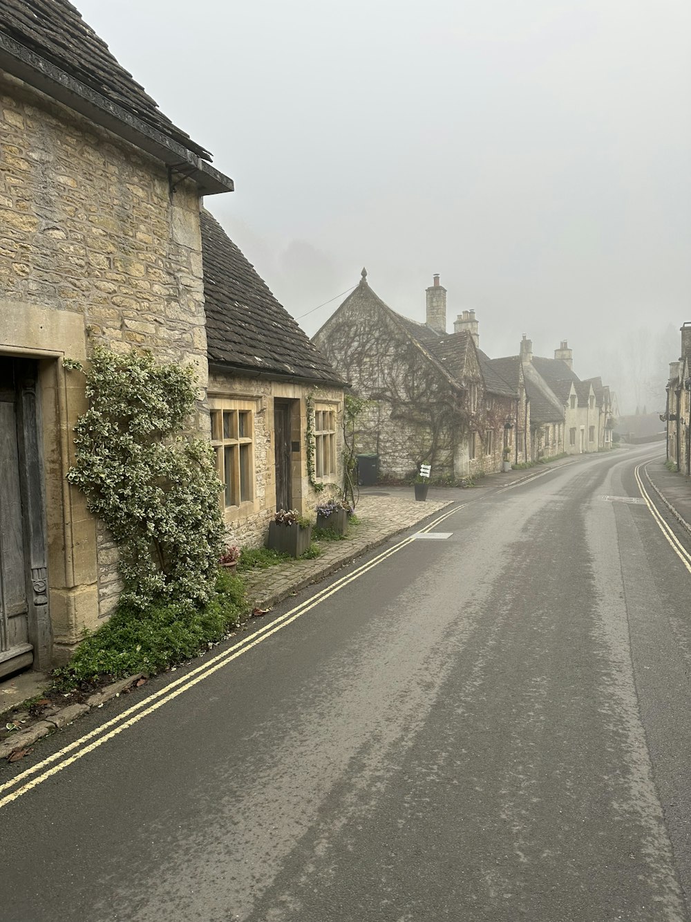 a foggy street lined with old stone buildings
