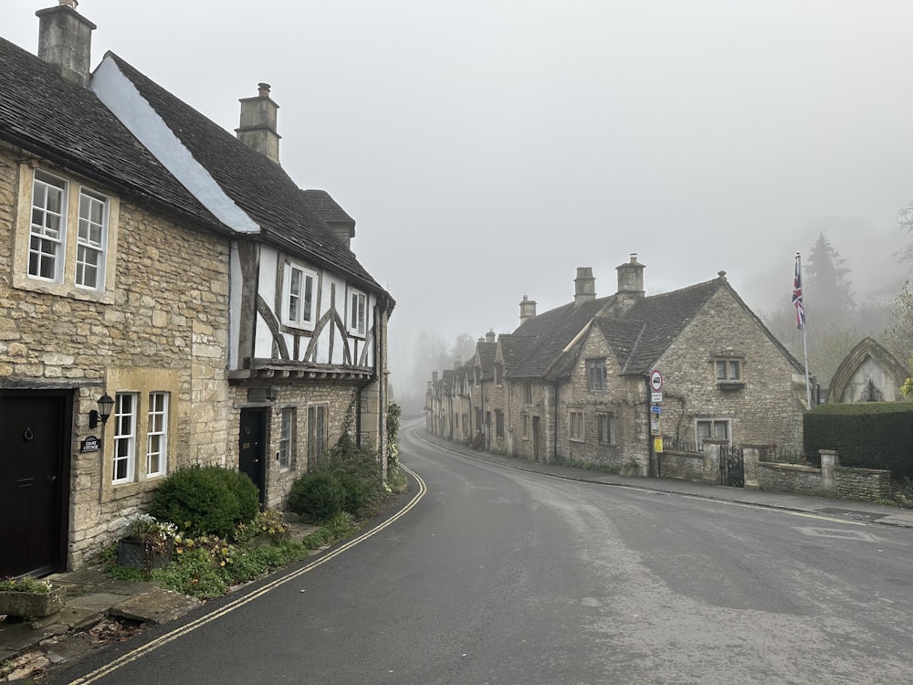 a street lined with stone buildings on a foggy day