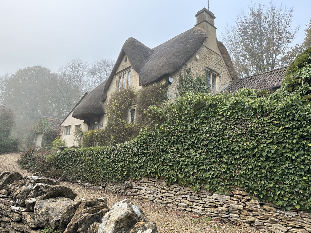 a house with a thatched roof next to a stone wall