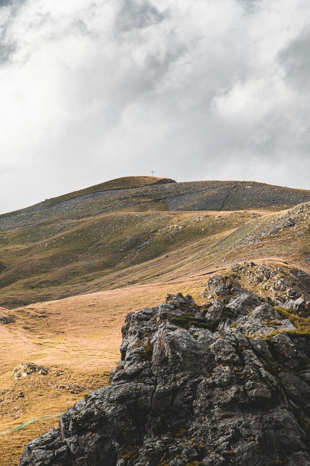 a lone sheep standing on top of a rocky hill