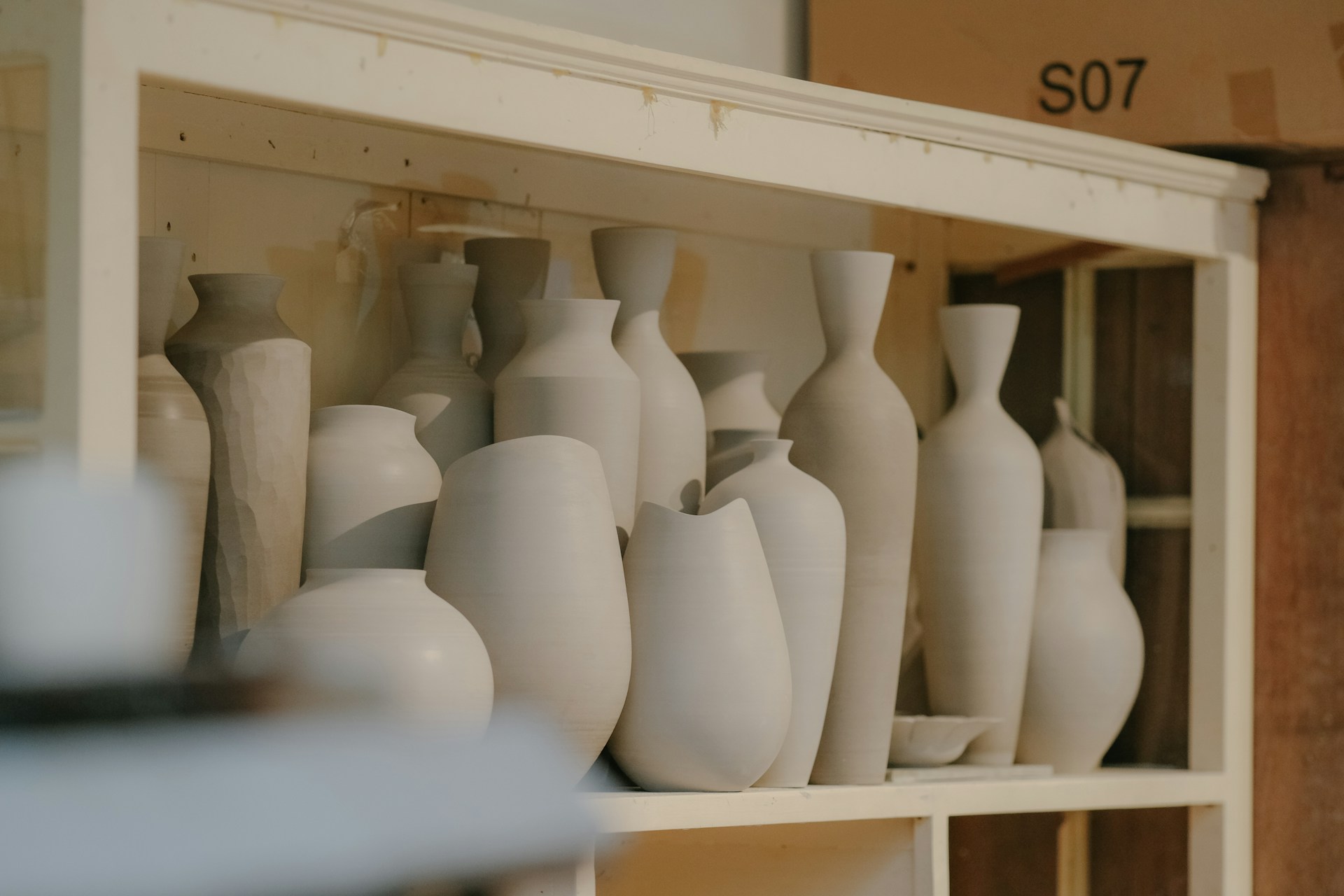a shelf filled with lots of white vases