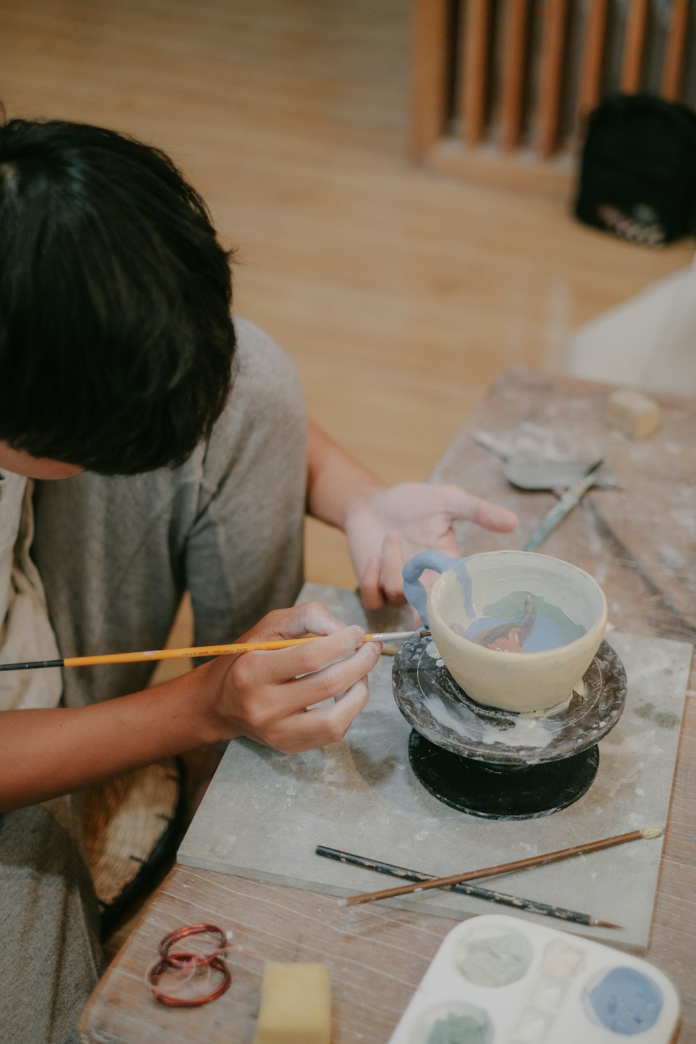 a boy is painting a bowl on a table