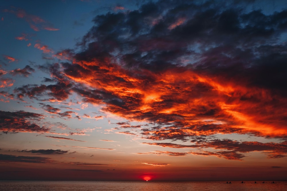 a sunset over a body of water with clouds in the sky