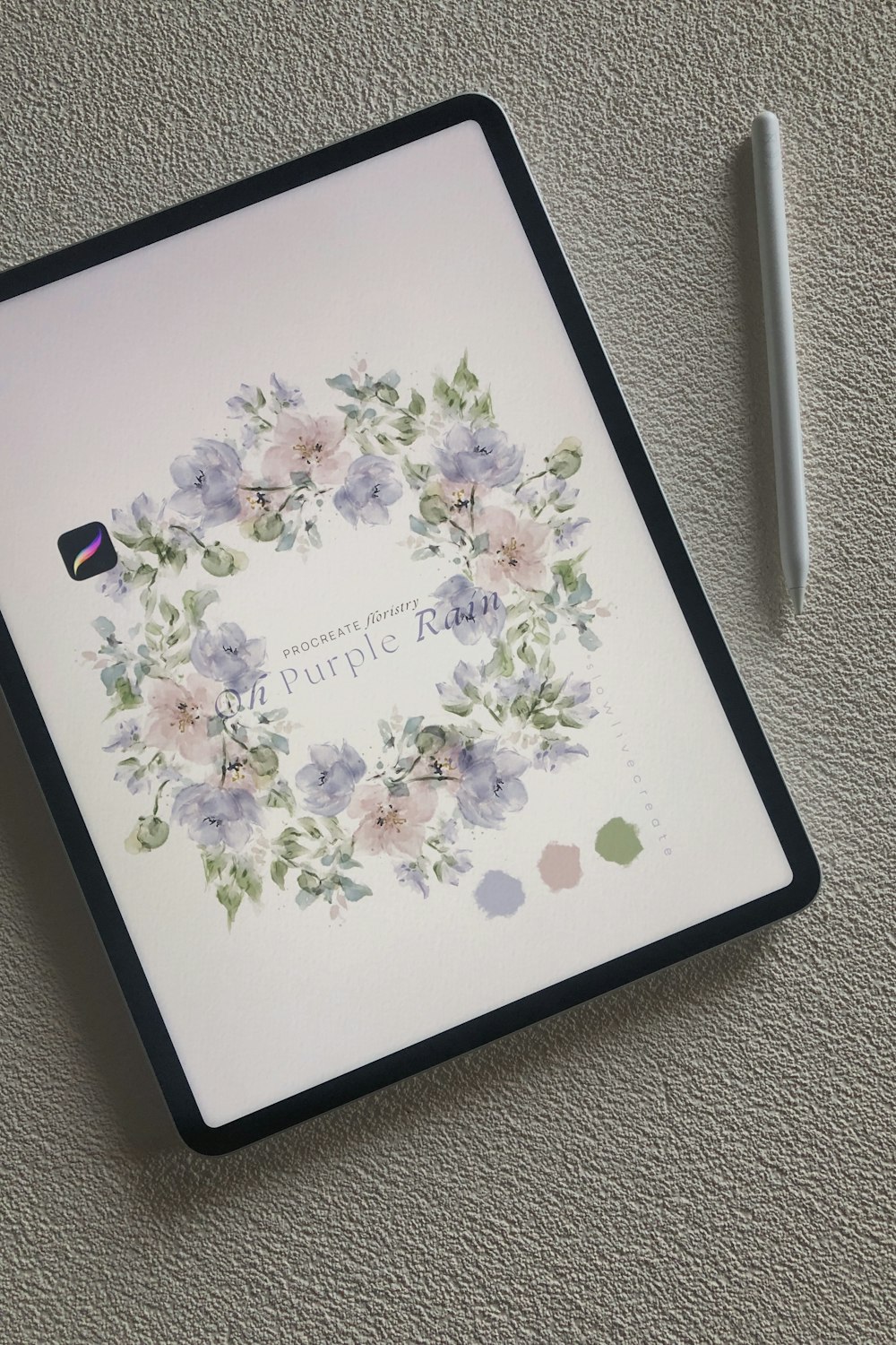 a notepad with a floral wreath on it next to a pen