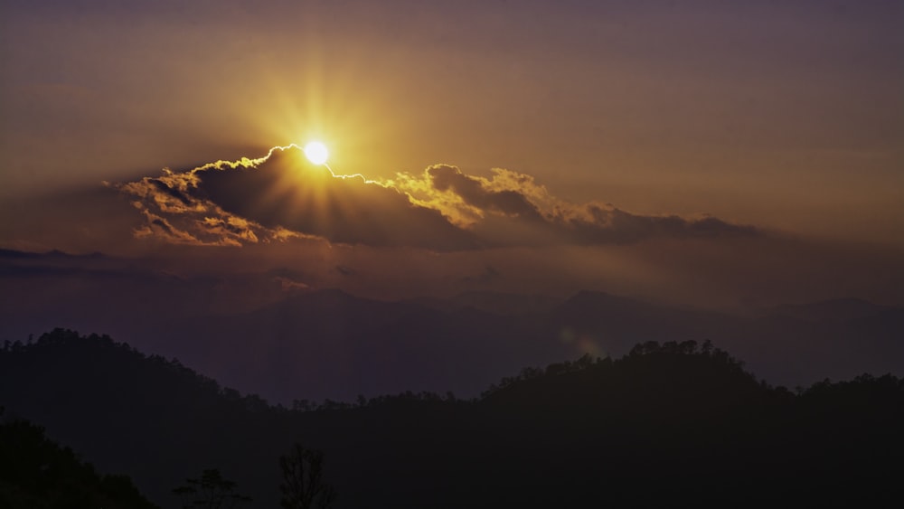 the sun is setting over a mountain range