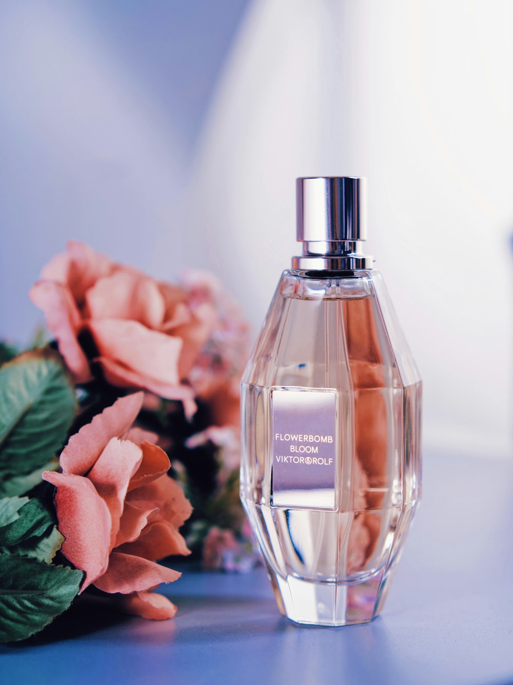 a bottle of perfume next to a bouquet of flowers