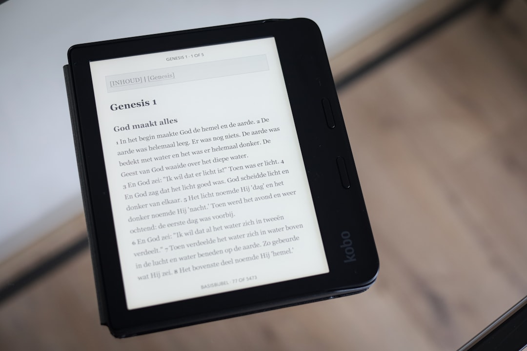 a person is holding a kindle on a table, Kobo on table.