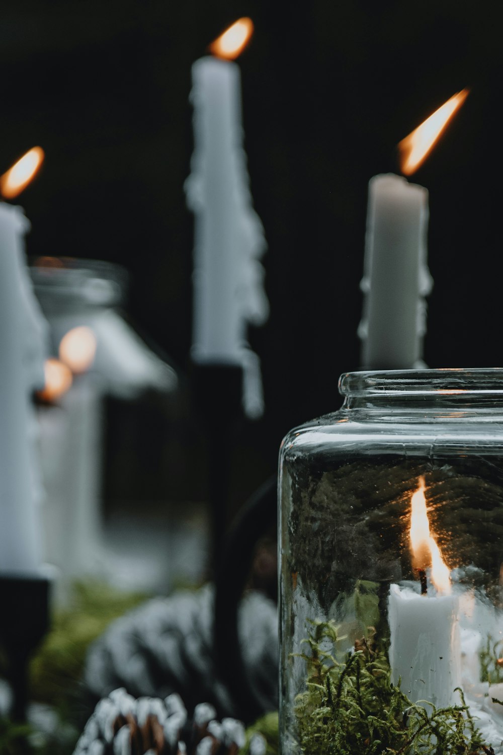 a glass jar filled with moss and lit candles