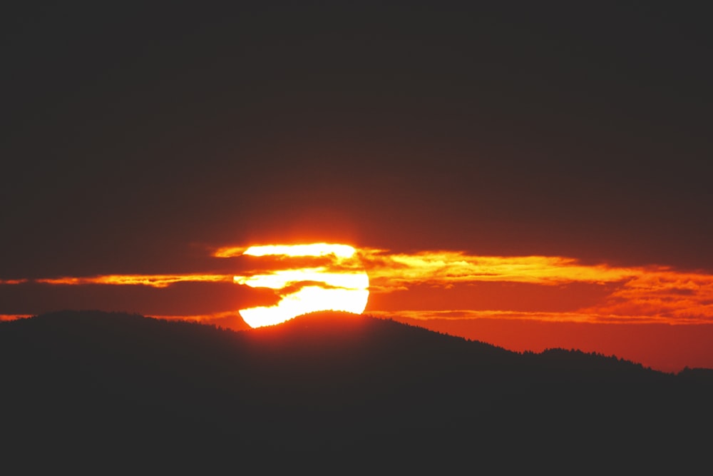 the sun is setting over a mountain range