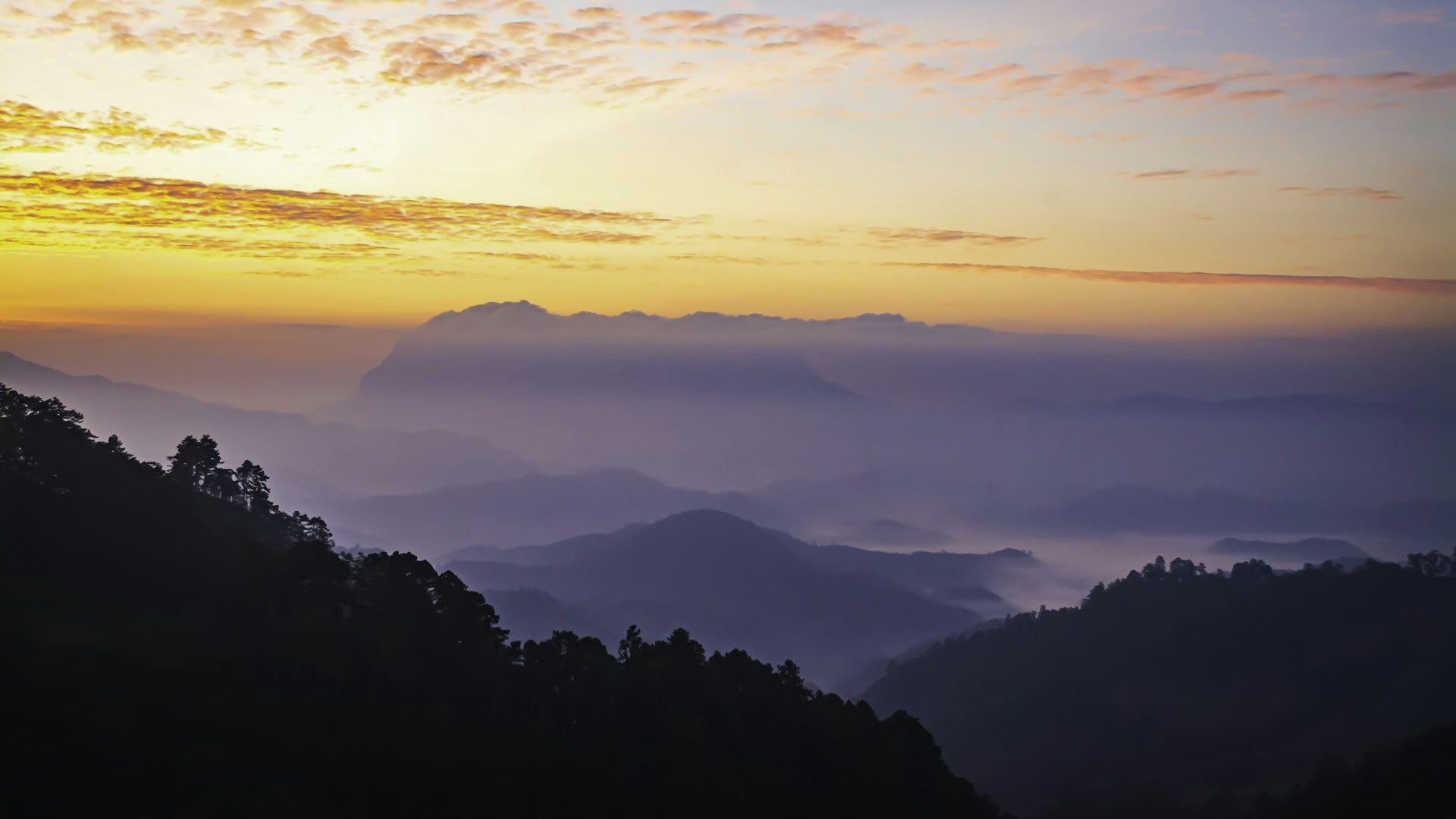 the sun is setting over a mountain range