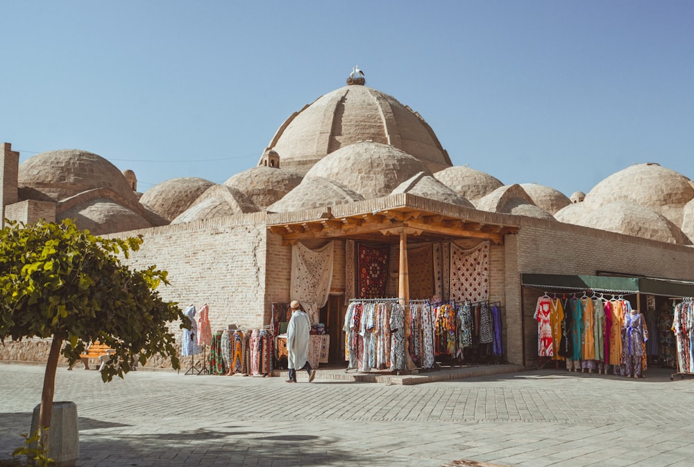 a man standing in front of a building with lots of clothes