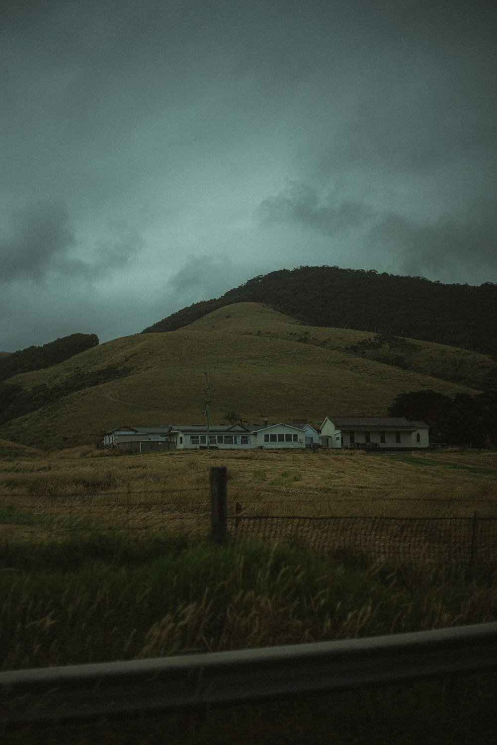 a house in the middle of a field with mountains in the background