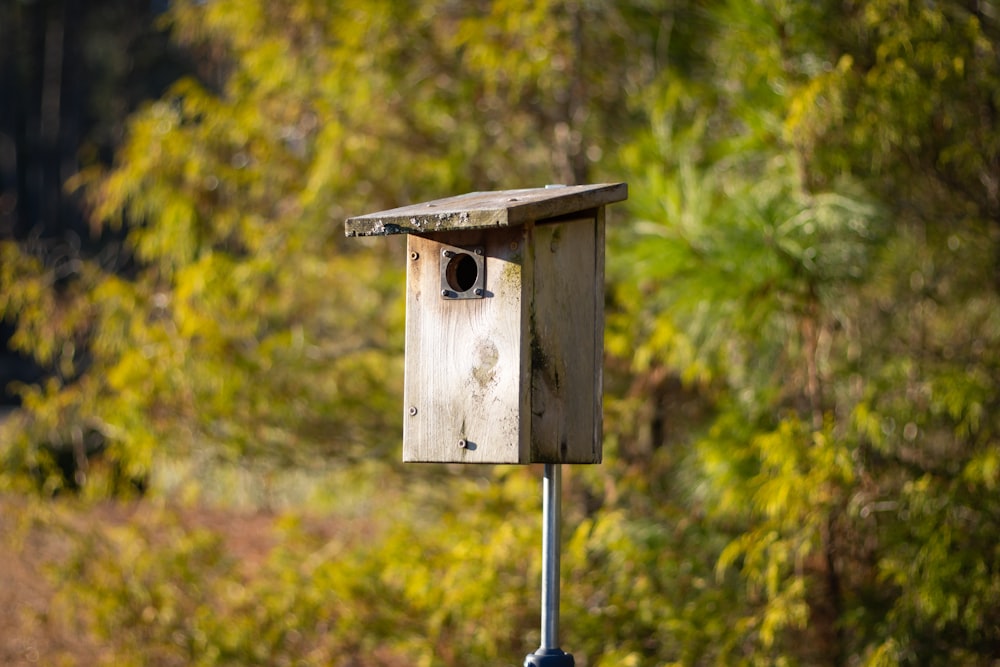 a wooden birdhouse sitting on top of a metal pole