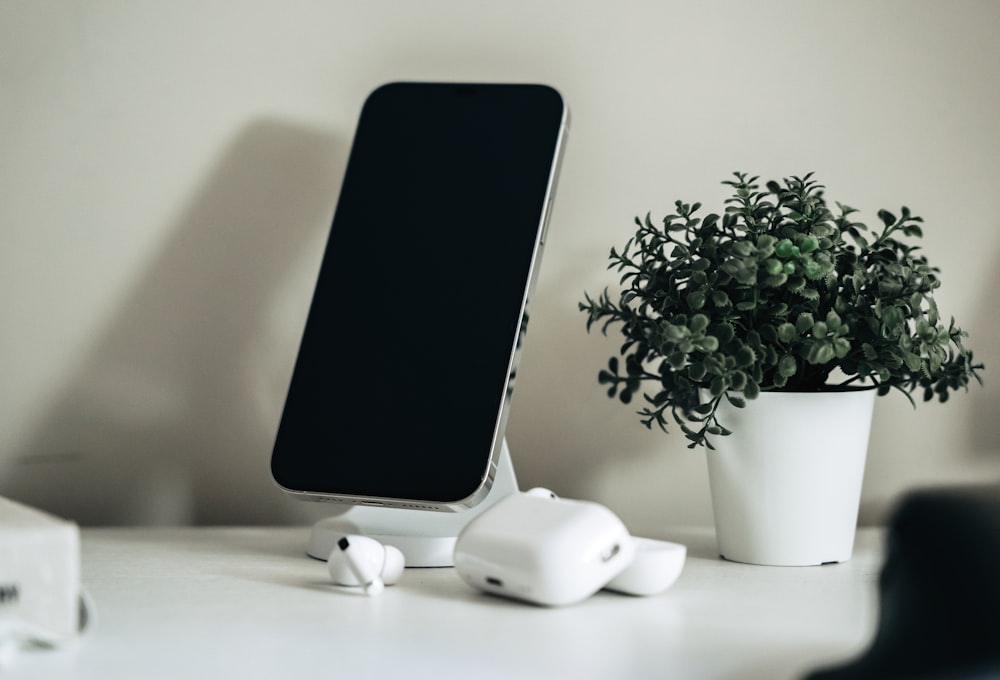 a cell phone sitting on top of a table next to a potted plant