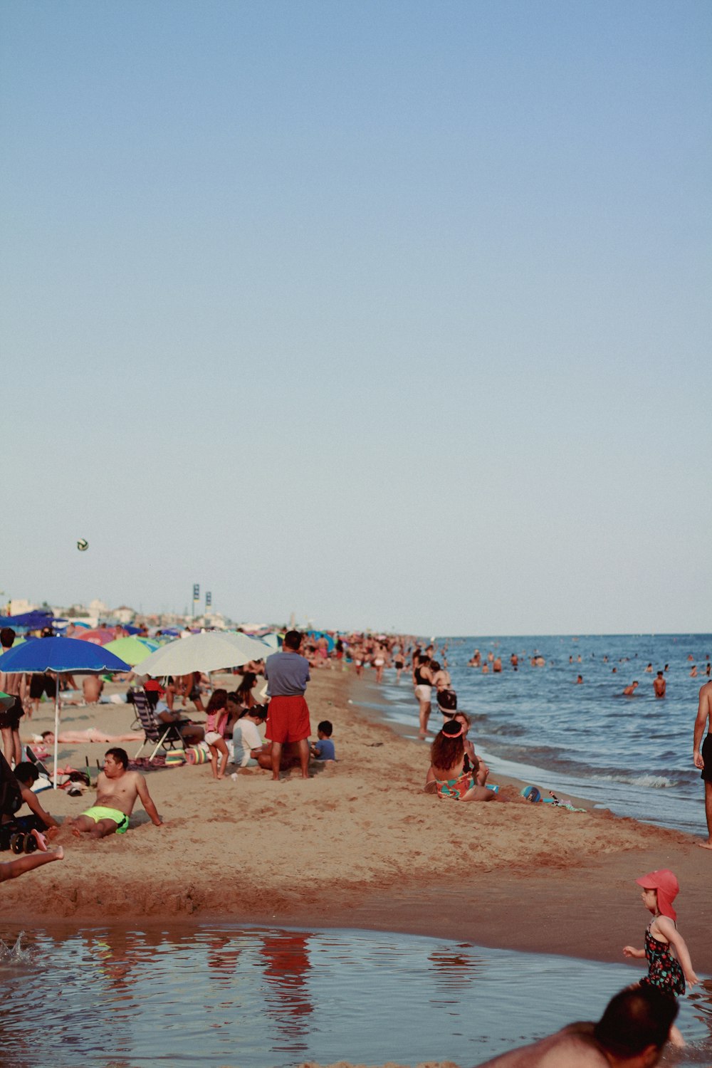 a crowded beach filled with people and umbrellas