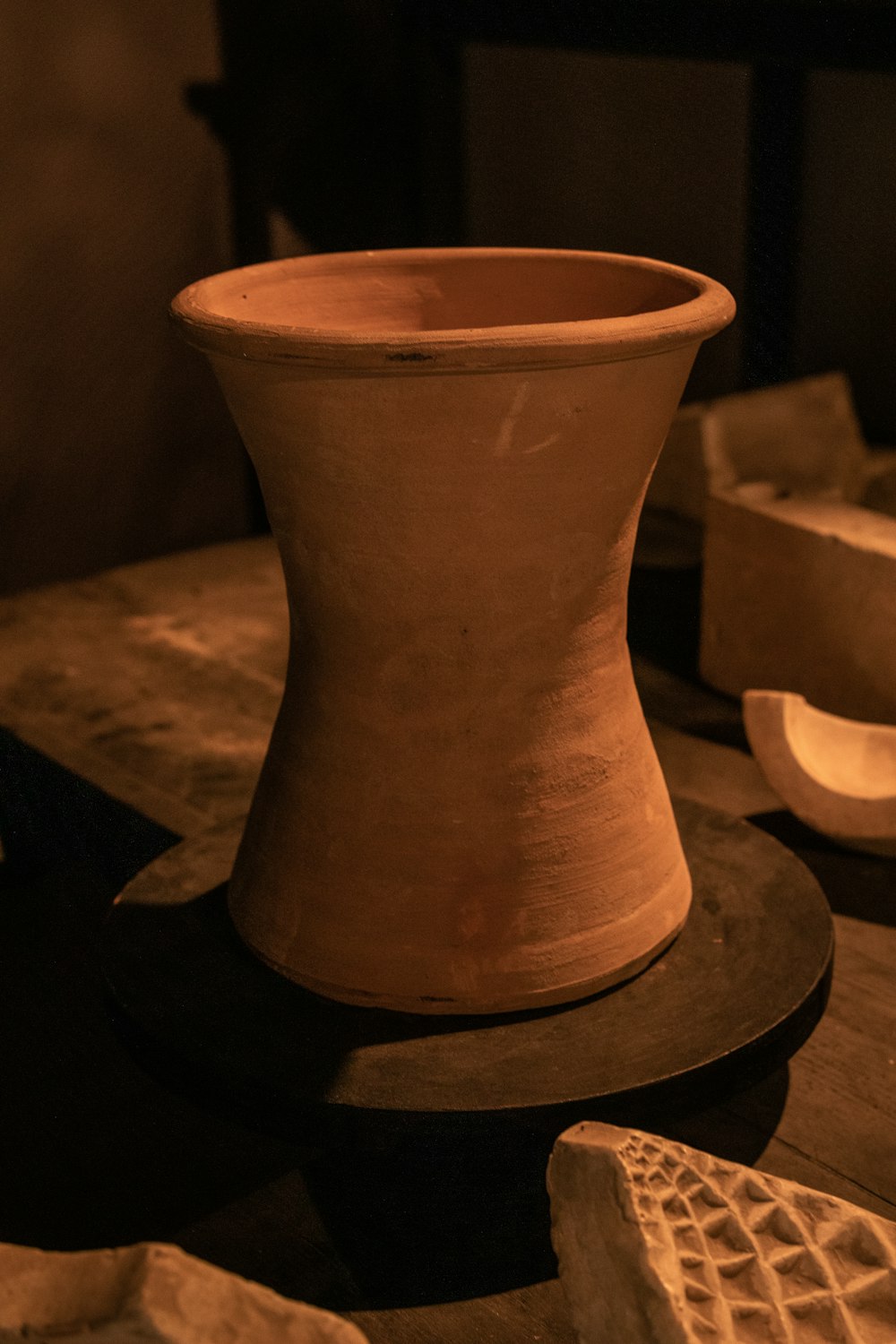 a clay vase sitting on top of a wooden table