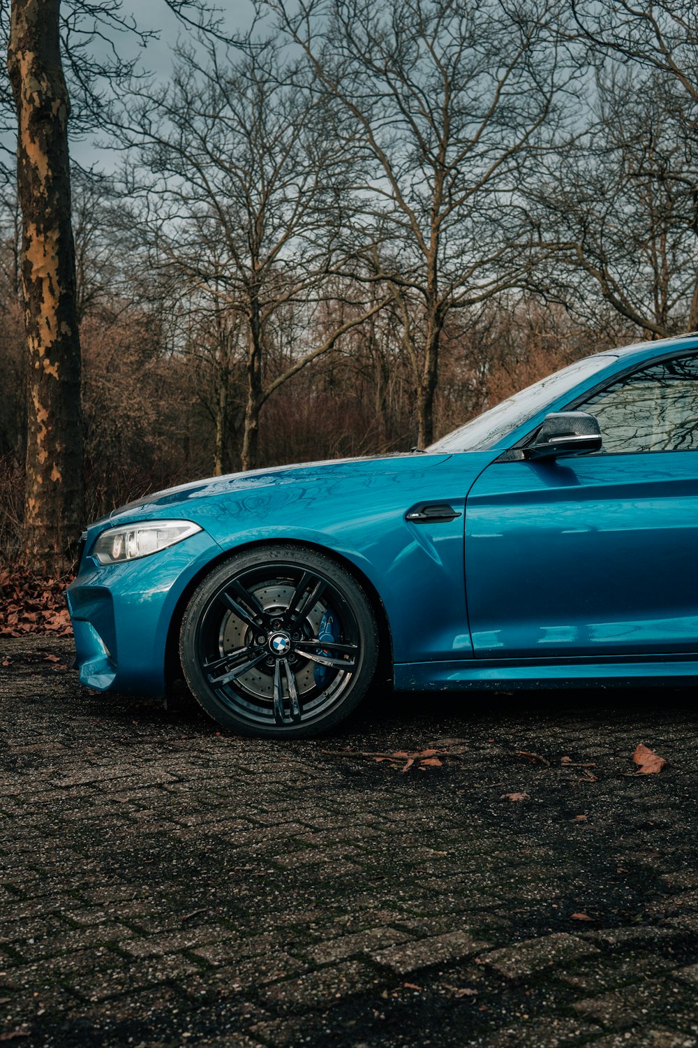 a blue car parked in front of some trees