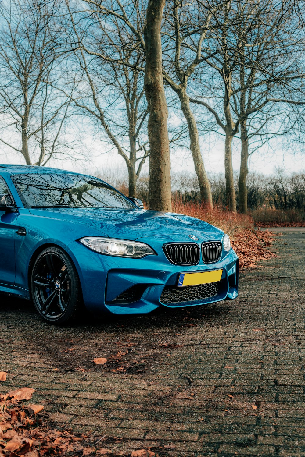 a blue sports car parked in front of some trees