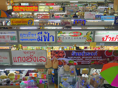 A bustling Thai market scene showcasing fresh herbs and traditional ingredients under vibrant umbrellas.