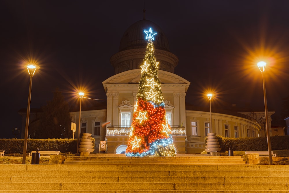 a lighted christmas tree in front of a building