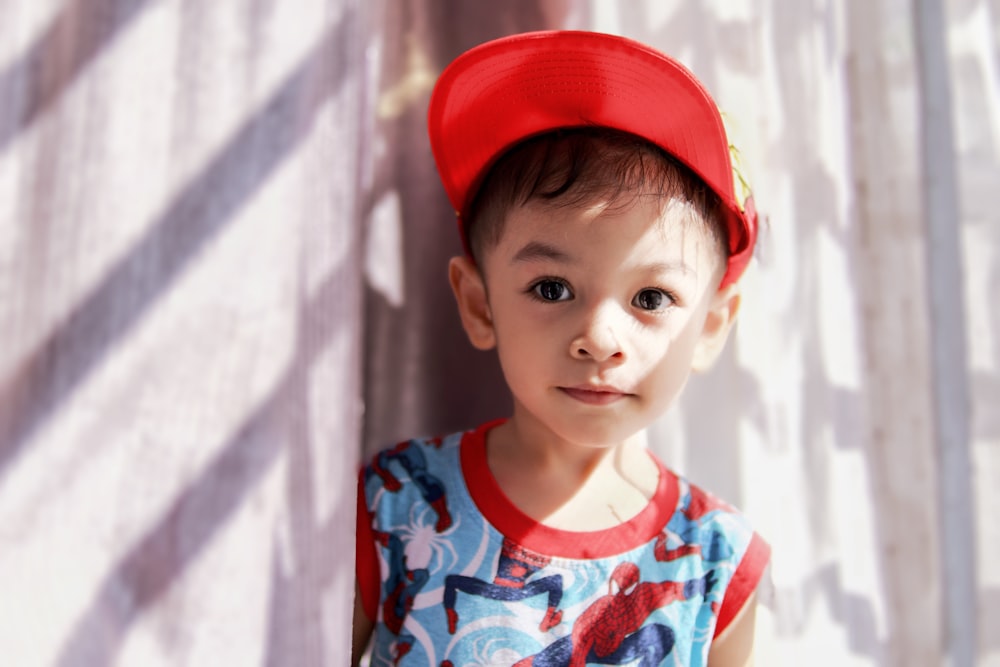 a young boy wearing a red baseball cap