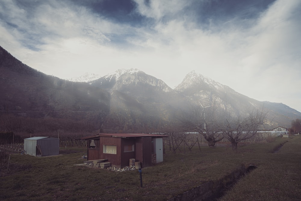 a small house in a field with mountains in the background