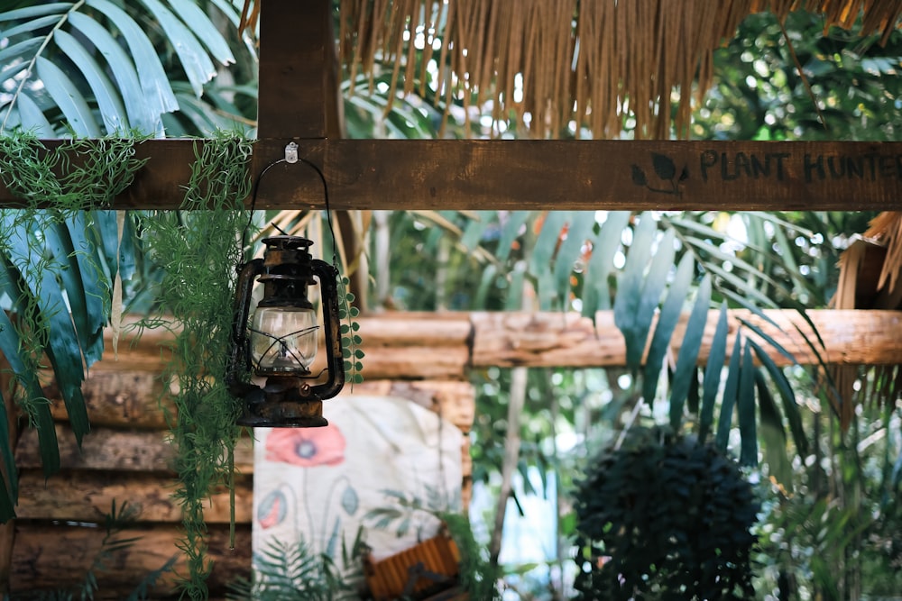 a lantern hanging from a wooden beam in a tropical setting