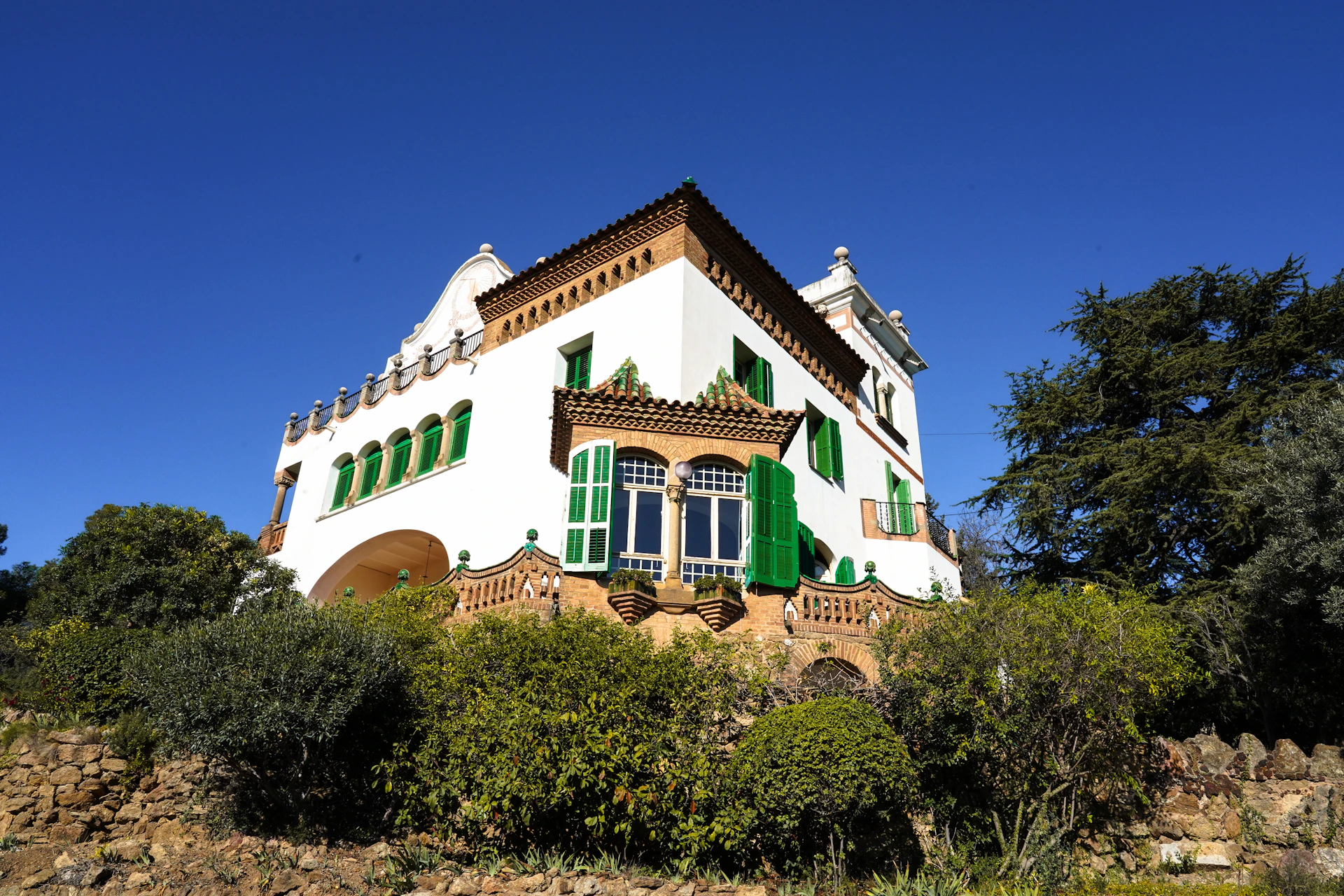 a large white house with green shutters on a hill